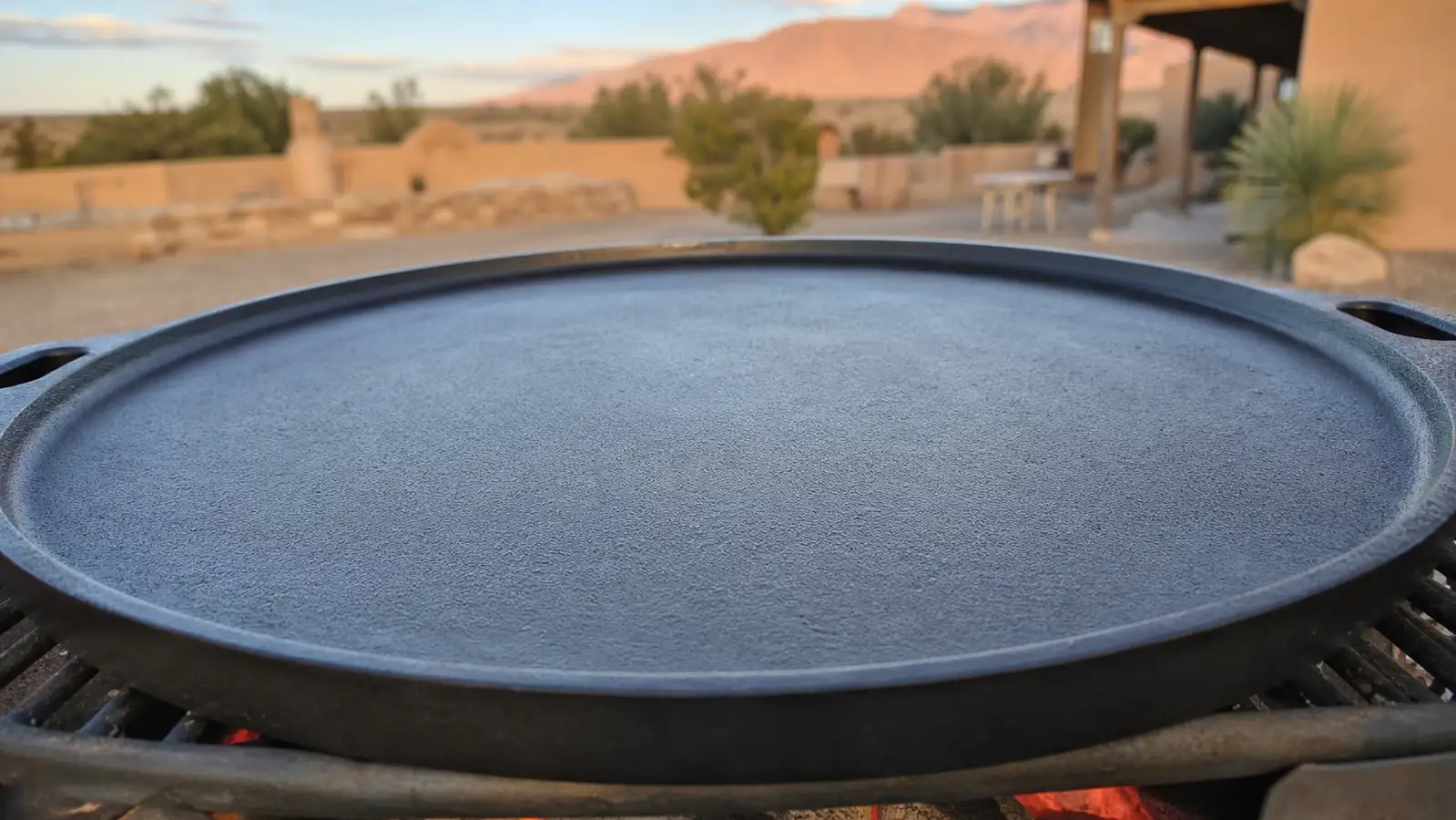 Close view of a cast iron griddle surface with a smooth, dark, glossy seasoning layer reflecting light