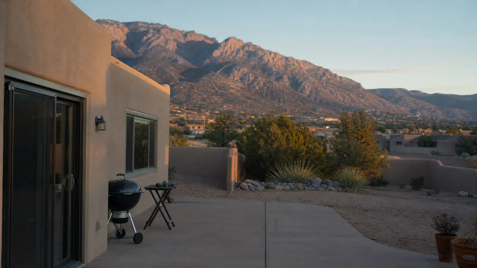 A cleared backyard patio in early morning light with only a black kettle grill and a small folding table remaining